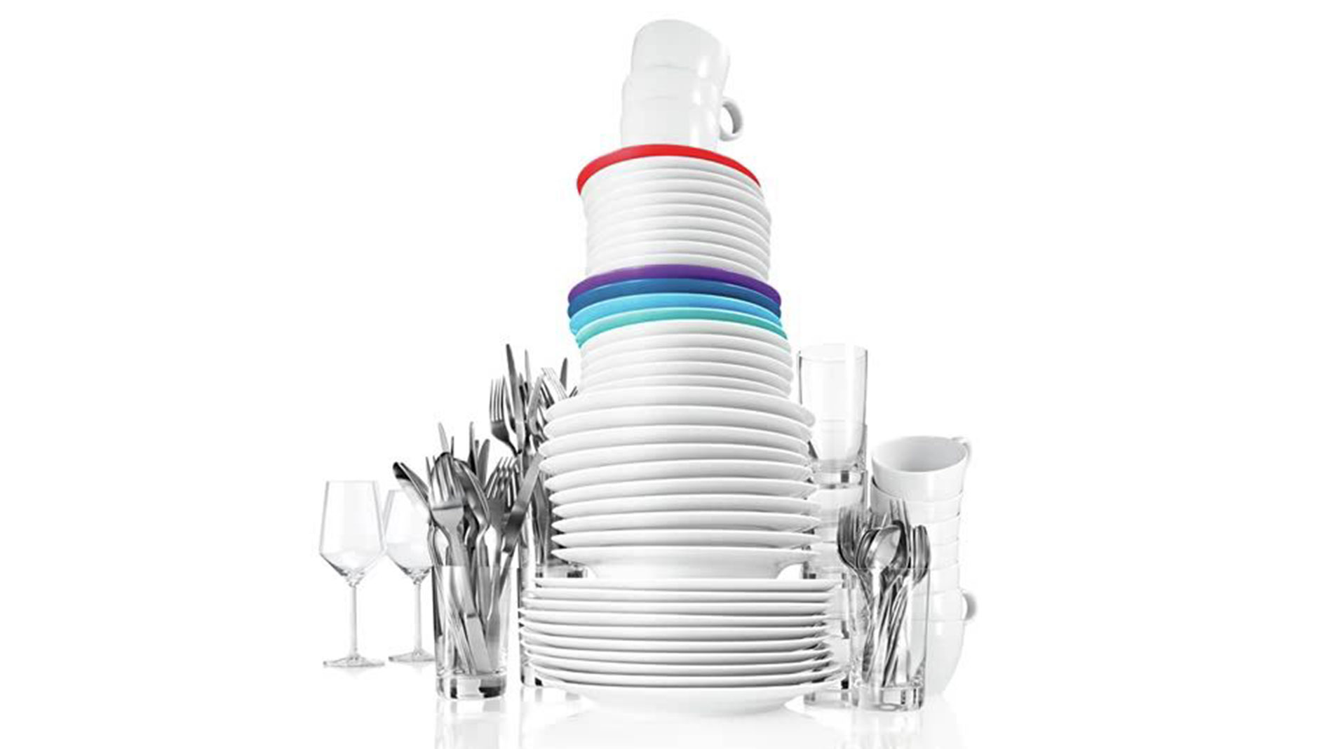Stos białych talerzy z kolorowymi rantami, obok kieliszki, kubki i sztućce w szklankach.